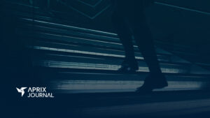Persona subiendo unas escaleras iluminadas en un entorno moderno, con el logotipo de "Aprix Journal" en la esquina inferior izquierda.